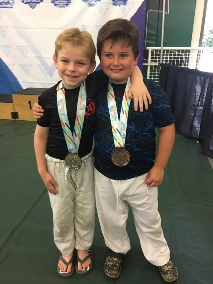 blake barba with a medal around his neck and another student with after winning a kids jiu jitsu competition