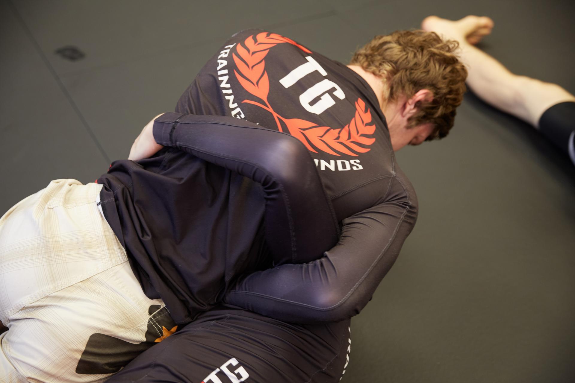 two men at an mma gym practicing a technique