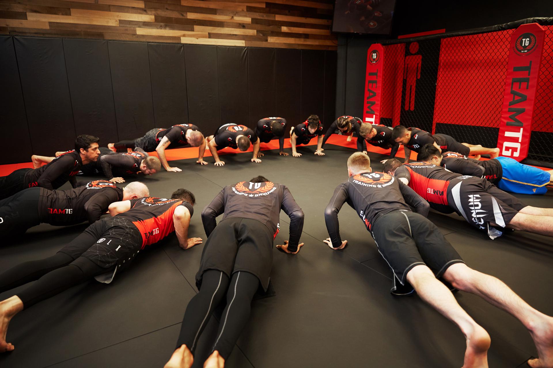 two men at an mma gym practicing a technique