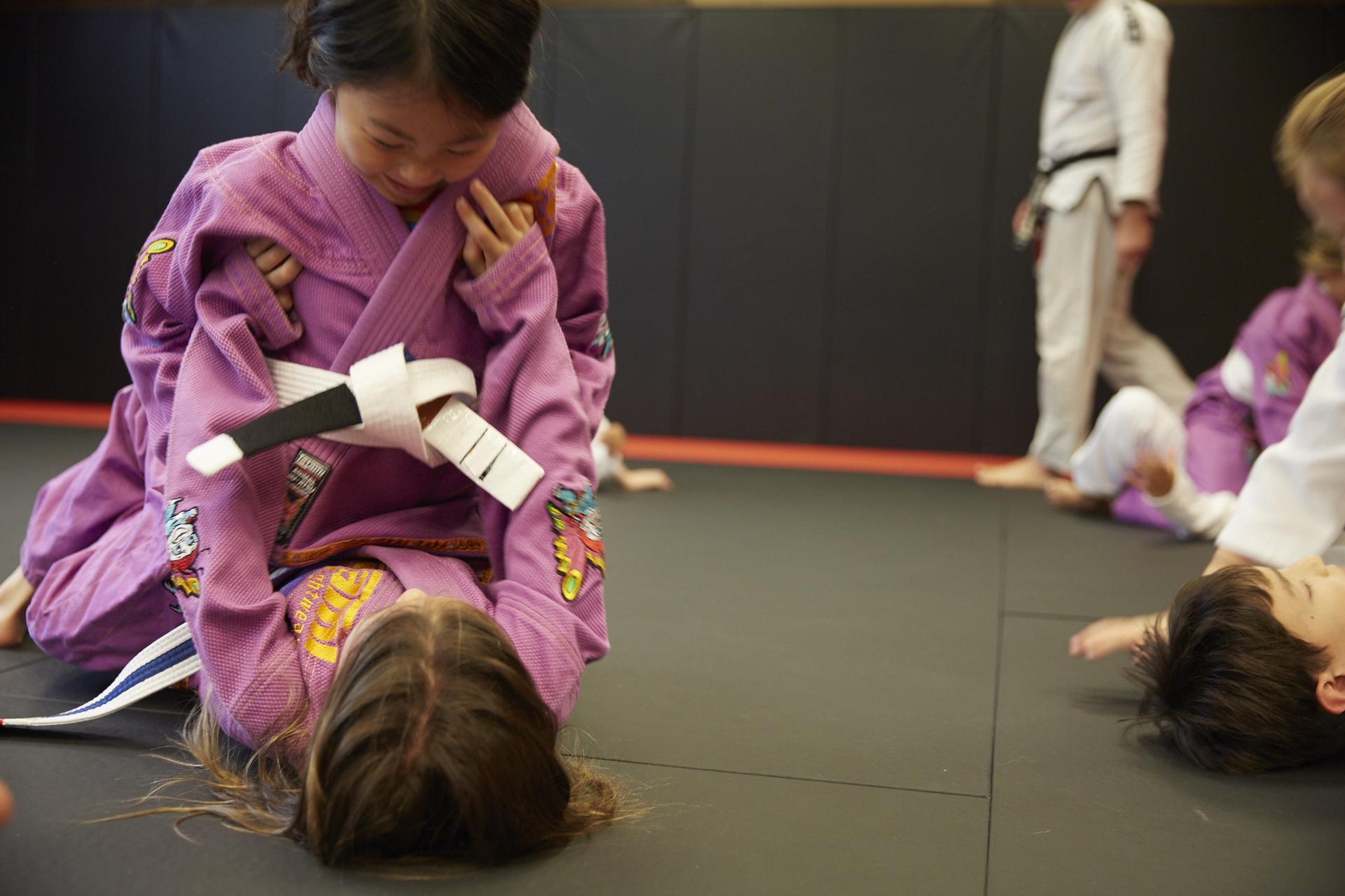 two girls smiling at each other a training grounds kids martial arts class