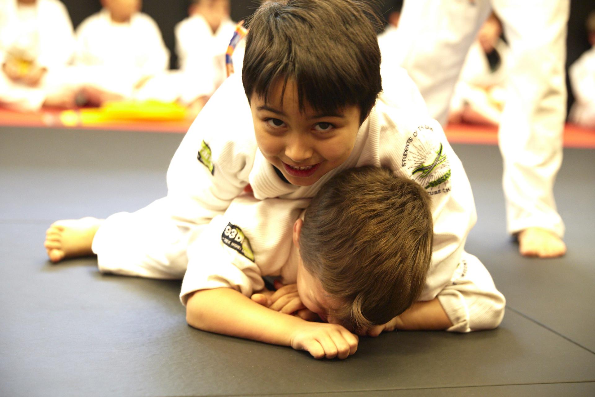 a boy smiling and feeling very confident with his performance in a brazilian jiu jitsu match at training grounds