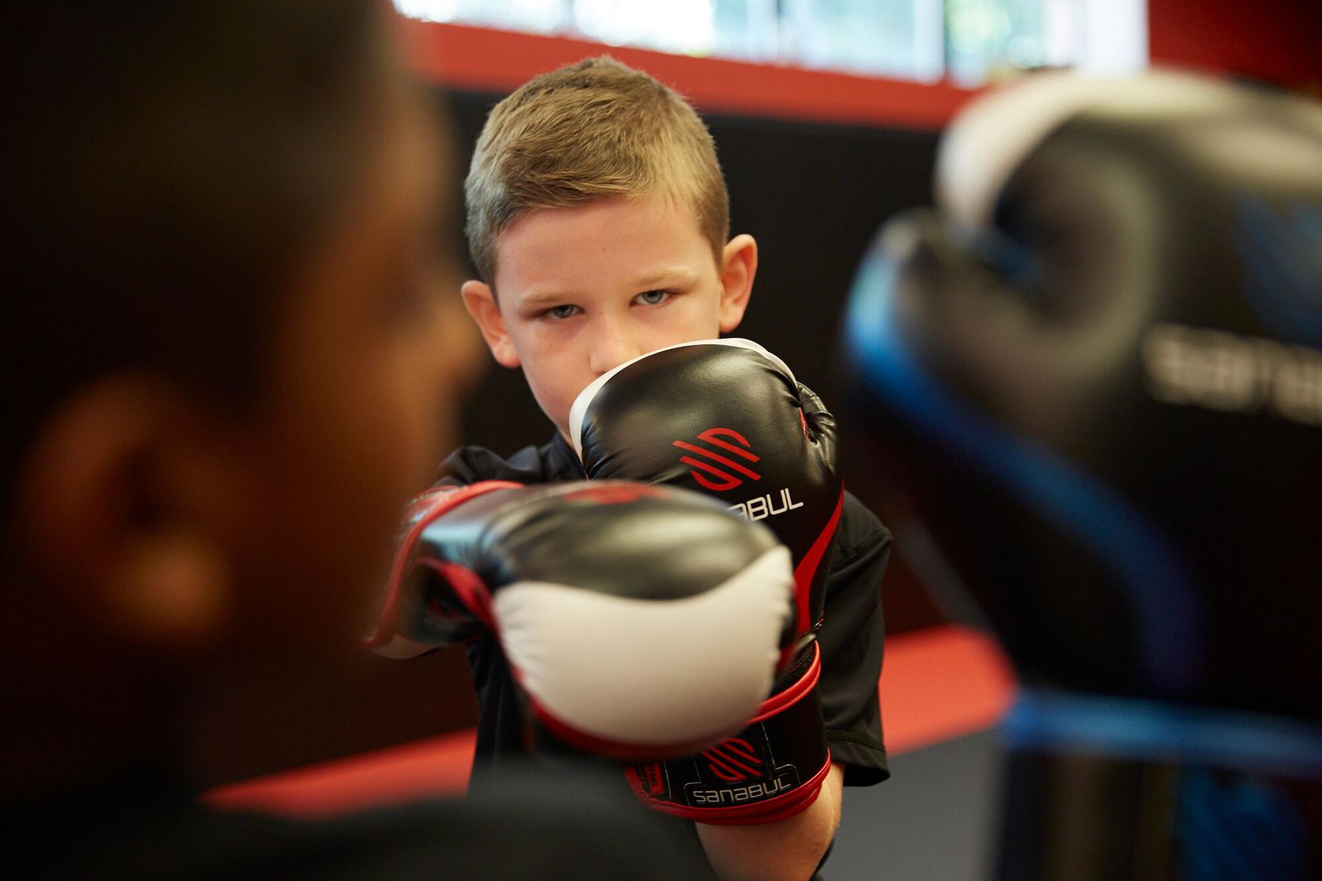 a child with gloves on throwing a punch in a martial art class
